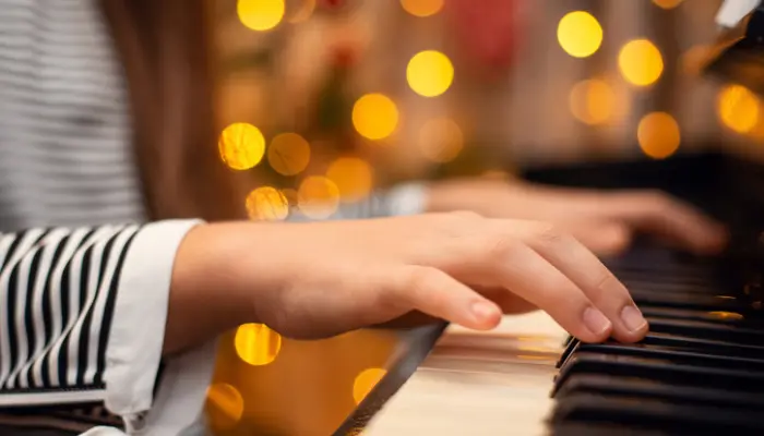 mains qui jouent du piano sur fond de lumières de fête